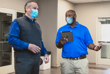 A ServiceMaster Clean technician and a client in an empty commercial space, both wearing protective face masks, discuss post construction cleaning in St. Cloud, Minnesota.