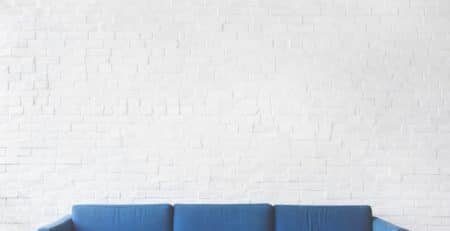 Blue sofa against a white brick wall
